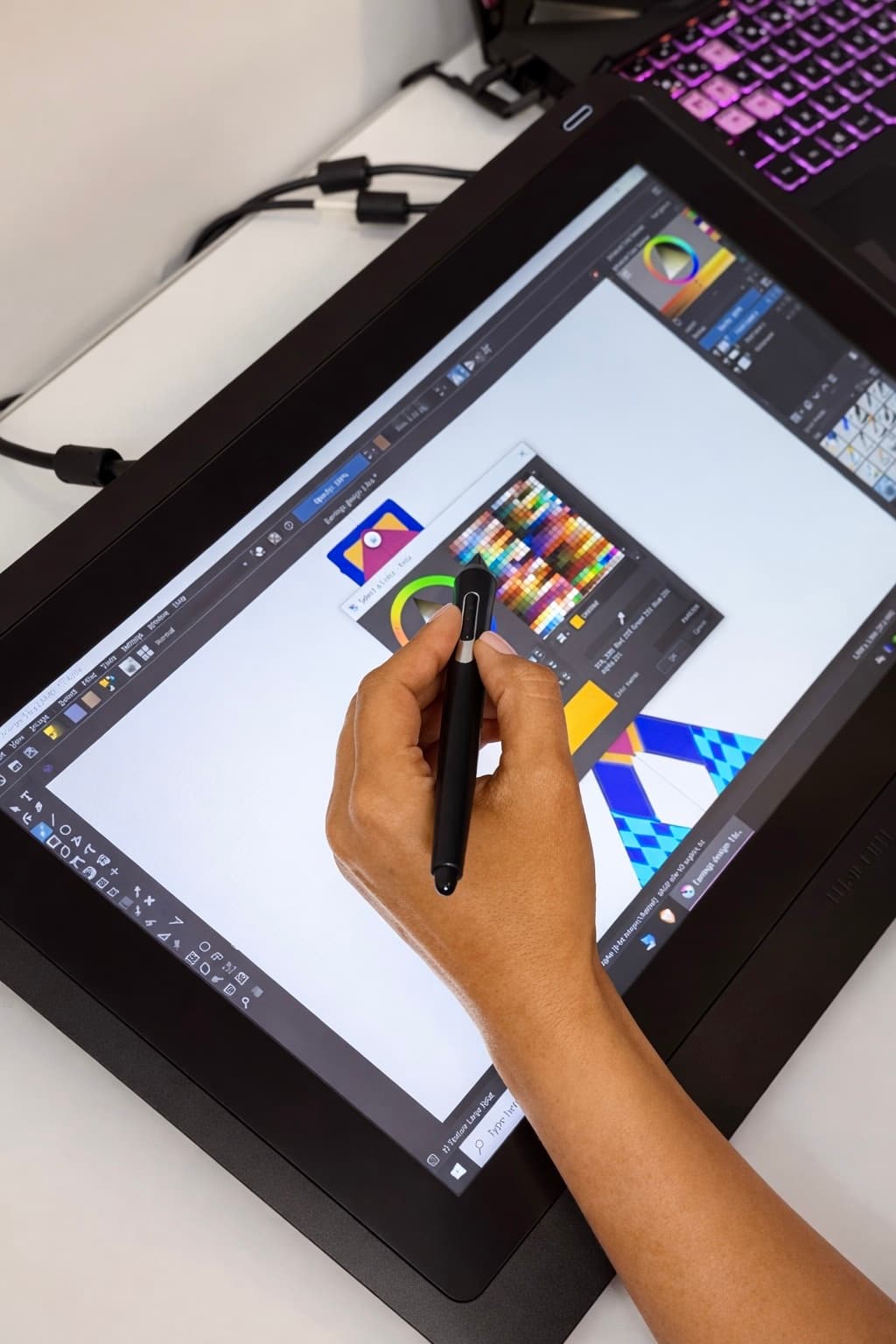 Artisan designing earring patterns on a digital drawing tablet in the studio